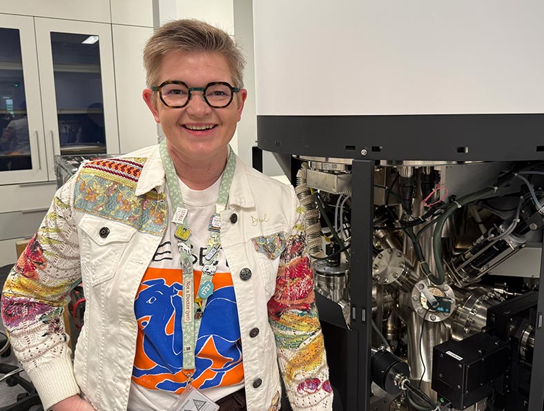 PhD researcher Sarah Polson alongside the X-ray Photoelectron Spectroscopy (XPS) system at the School of Physical and Chemical Sciences, Te Whare Wānanga o Waitaha University of Canterbury. Photo by Sarah Polson.